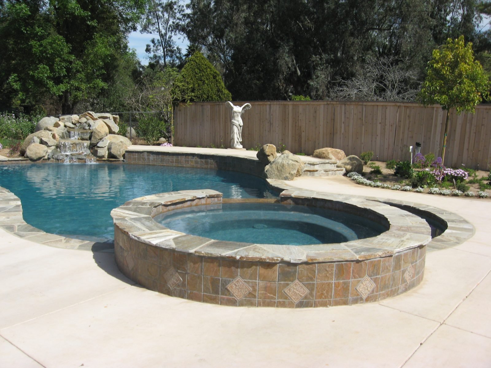 Earwicker Residence — Pool and round raised spa with a rock waterfall