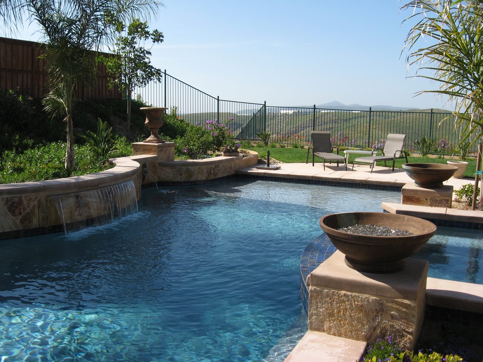Modern rectangular pool with sheet-descent water wall and attached outdoor kitchen, built by Ultrascape in San Diego County