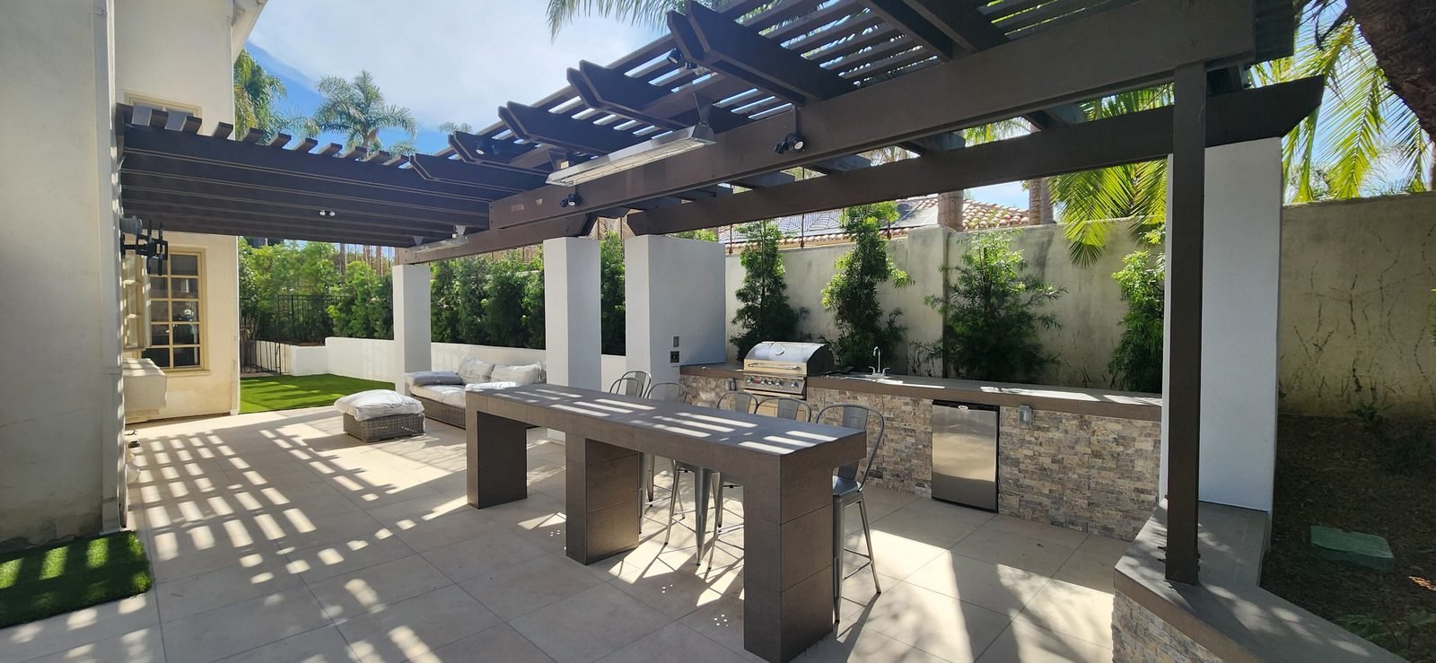 Covered outdoor kitchen and stacked-stone bar under a structural colonnade